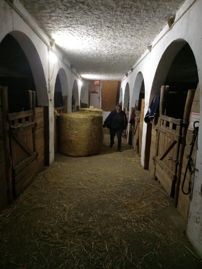 Istálló belseje szalmával felszórt folyosóval és nagy szénabálával